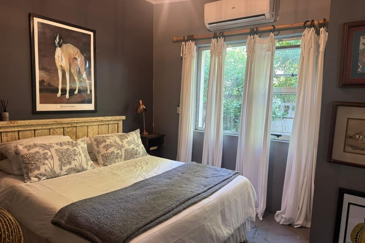 A bedroom featuring dark painted walls, a wall-mounted split-system air conditioner, and a window with natural light.