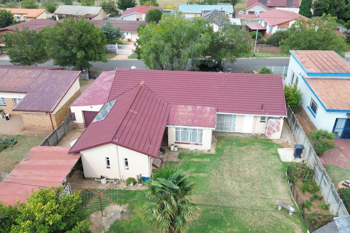 Aerial view of a residential property featuring a tiled roof, private garden, and perimeter walling in a suburban neighborhood setting.