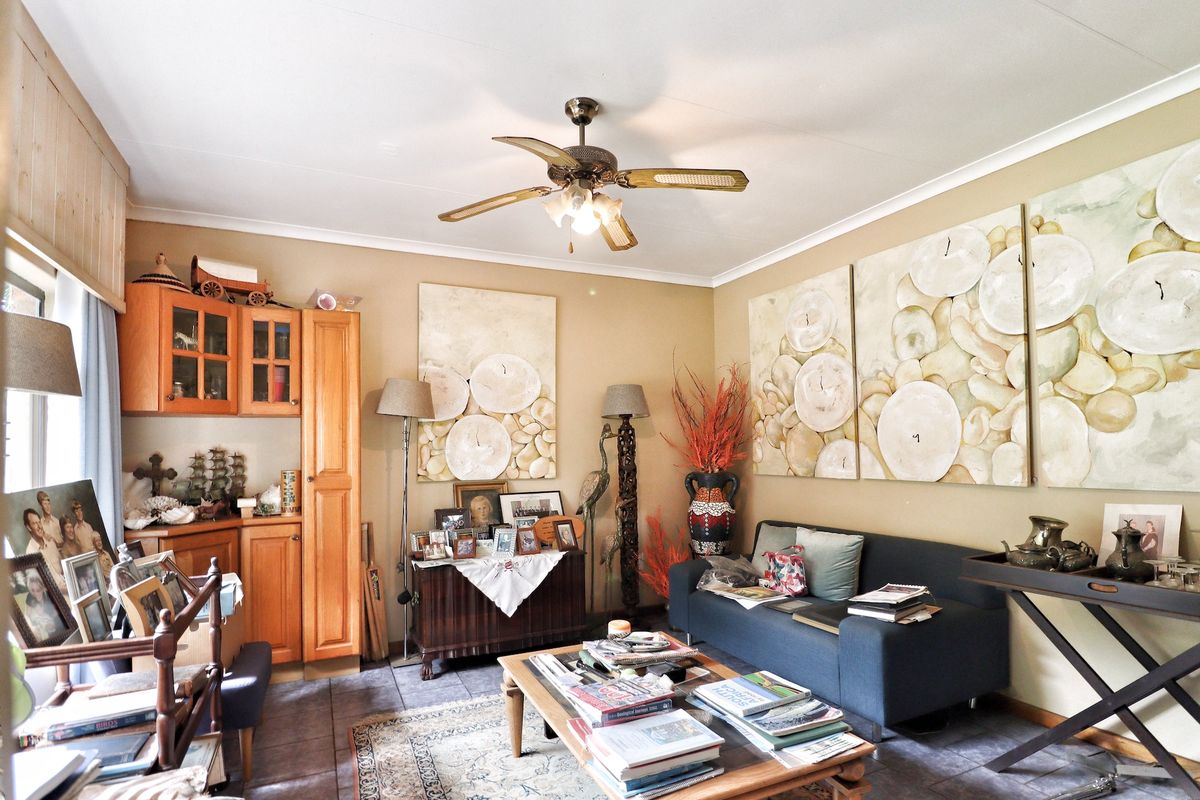 A living room featuring tiled flooring, built-in wooden cabinetry, and a ceiling fan.
