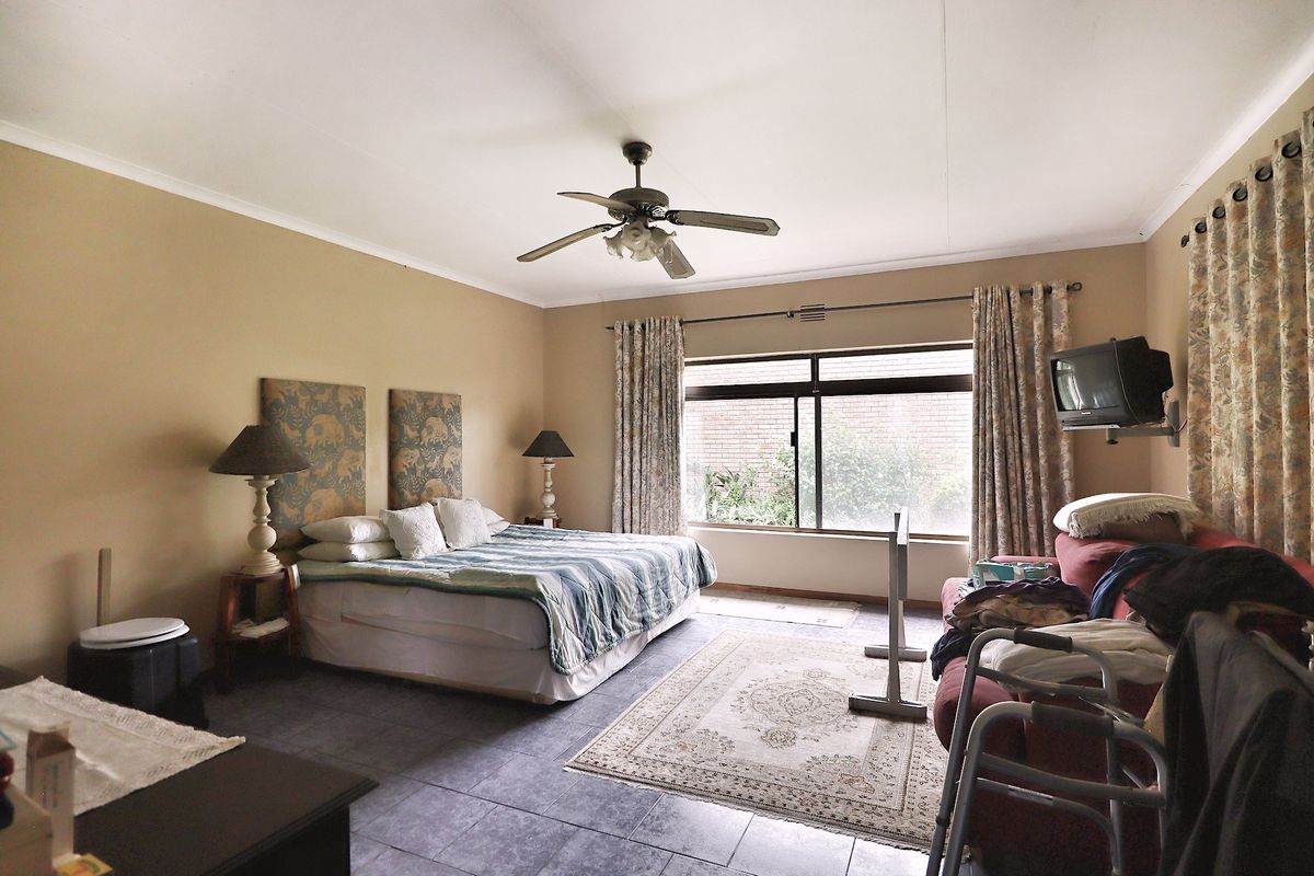 Spacious bedroom featuring tiled flooring, a ceiling fan, and large windows allowing for natural light.