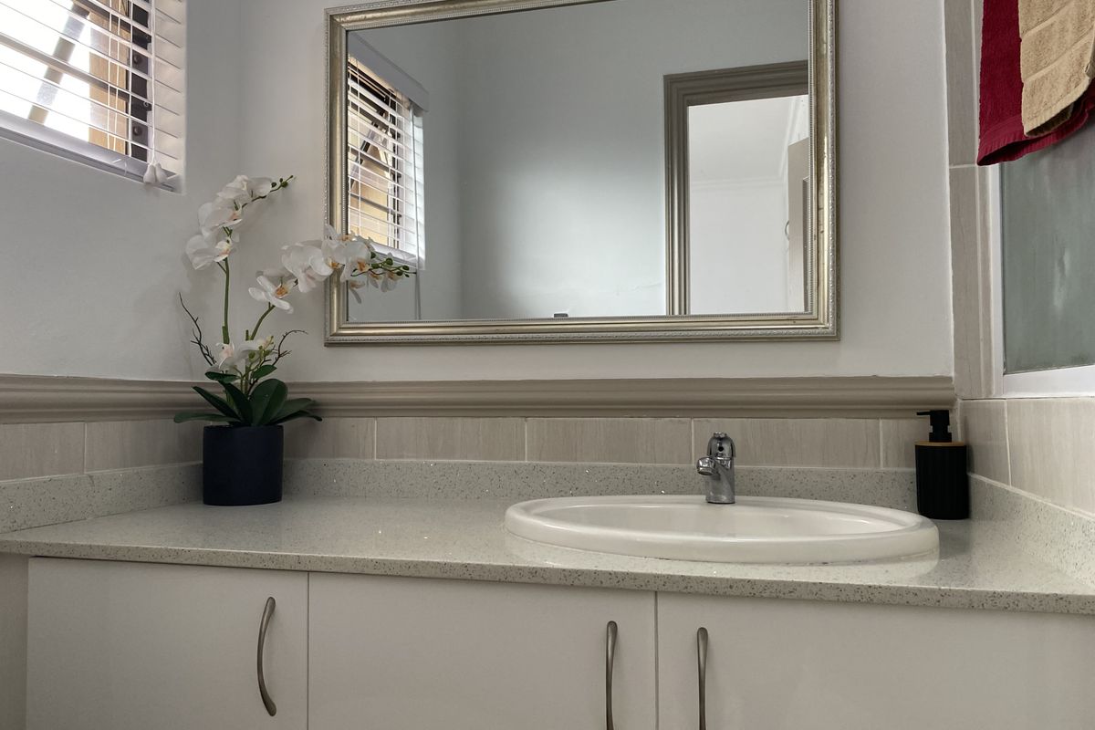 A clean and well-maintained bathroom vanity featuring a stone countertop, integrated sink, and a large wall-mounted mirror.
