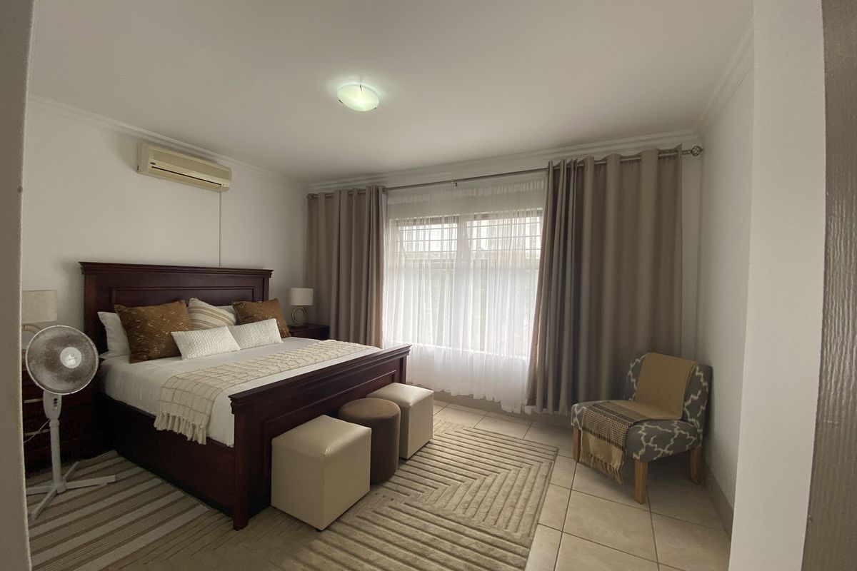 A bedroom featuring tiled flooring and a wall-mounted split-system air conditioner unit.