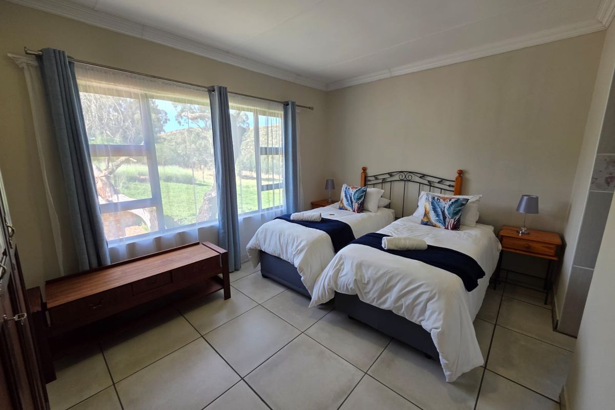 A bright bedroom featuring large windows with natural light, tiled flooring, and crown molding, offering a comfortable and functional living space.