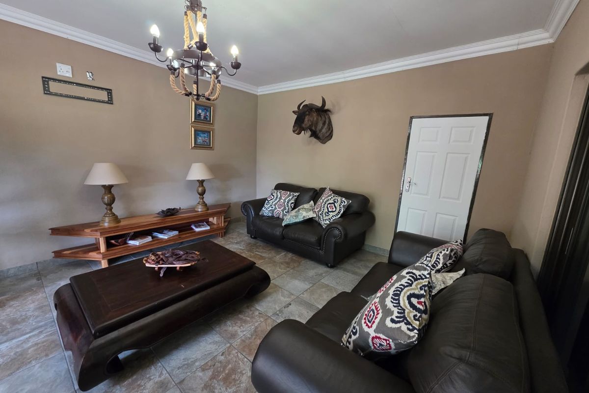 A comfortable living room featuring tiled flooring, crown molding, and a decorative chandelier, providing a warm and inviting space for relaxation.
