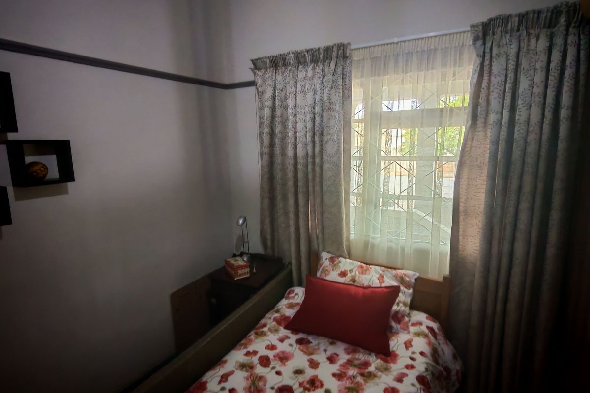A compact bedroom featuring a window with security bars, built-in wardrobe, and picture rail molding.