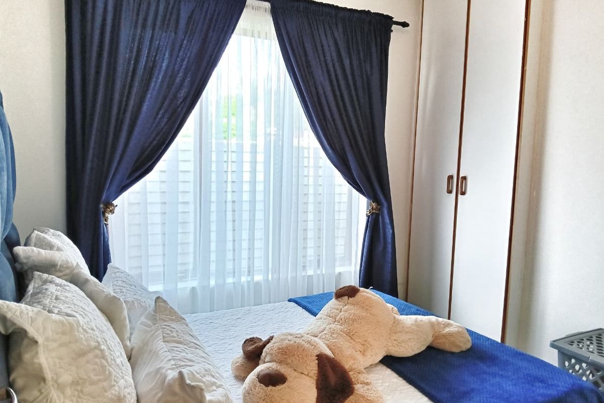 A cozy bedroom featuring a built-in wardrobe and natural light through a window with curtains.