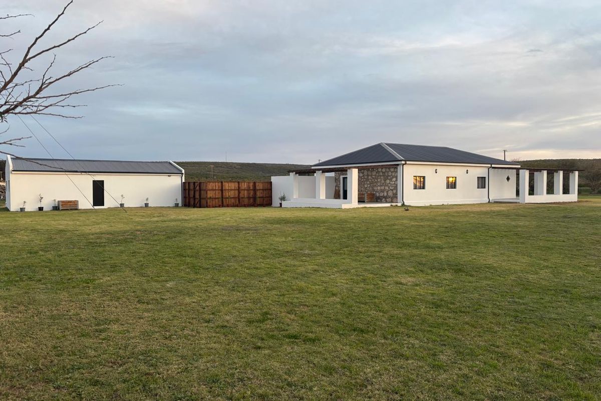A well-maintained farm property featuring a main residence with stone accents, a separate outbuilding, and expansive surrounding lawn areas.