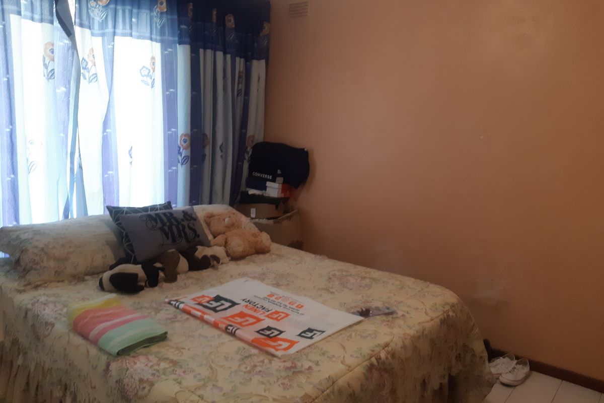 A bedroom featuring tiled flooring and curtain rails, currently requiring cosmetic updates to the wall finishes.