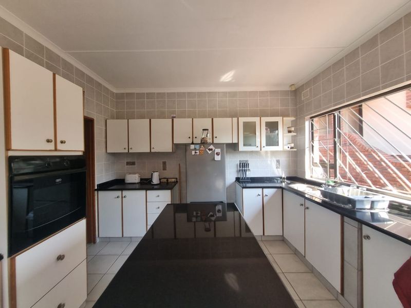 Functional kitchen featuring granite countertops, a central island, tiled backsplash, and built-in oven, offering a practical layout with ample storage cabinetry.