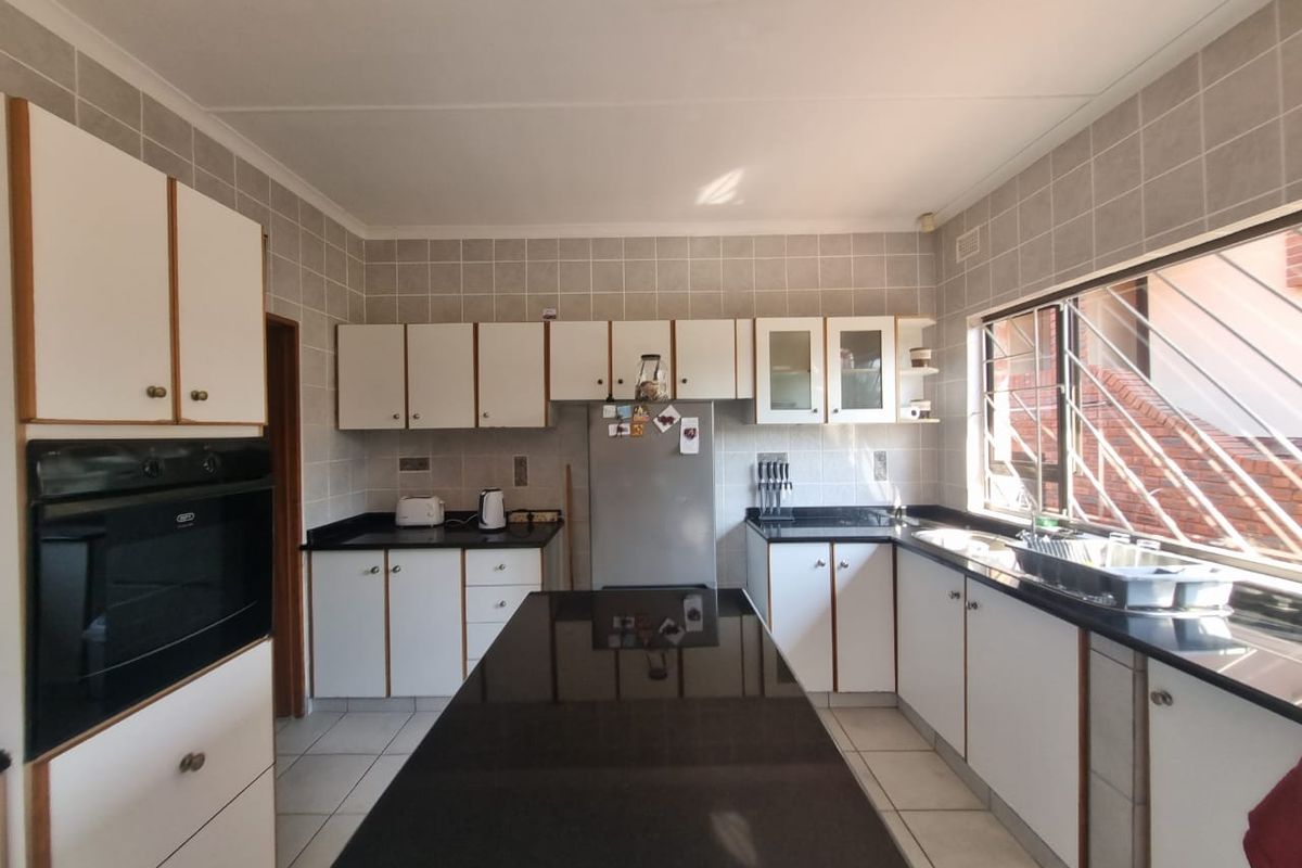 Functional kitchen featuring granite countertops, a central island, tiled backsplash, and built-in oven, offering a practical layout with ample storage cabinetry.