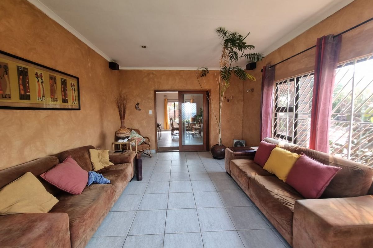Spacious living room featuring tiled flooring, textured wall finishes, and a sliding glass door providing access to the adjacent dining area.