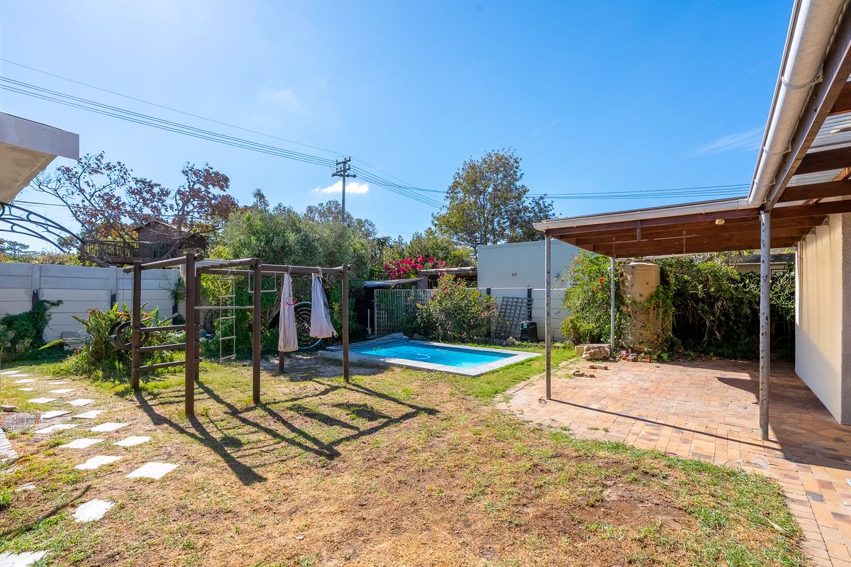 Rear garden featuring a paved patio area, a small swimming pool, and established landscaping.