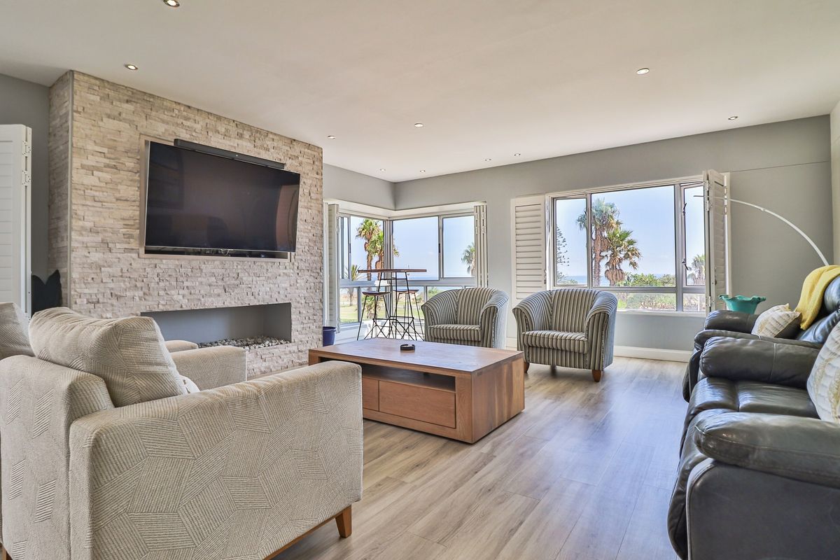 Spacious living room featuring a stone-clad feature wall with a built-in fireplace and large windows offering natural light and scenic views.