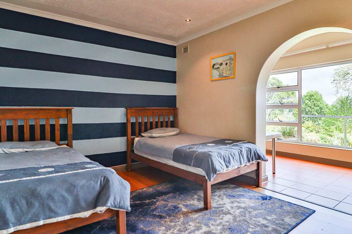 A bedroom featuring an arched entryway leading to an adjoining sunroom with large windows and tiled flooring.