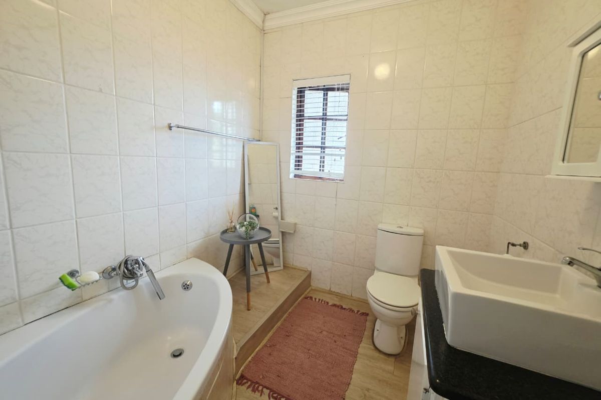A functional bathroom featuring a built-in bathtub, vessel sink on a vanity countertop, and tiled wall finishes.