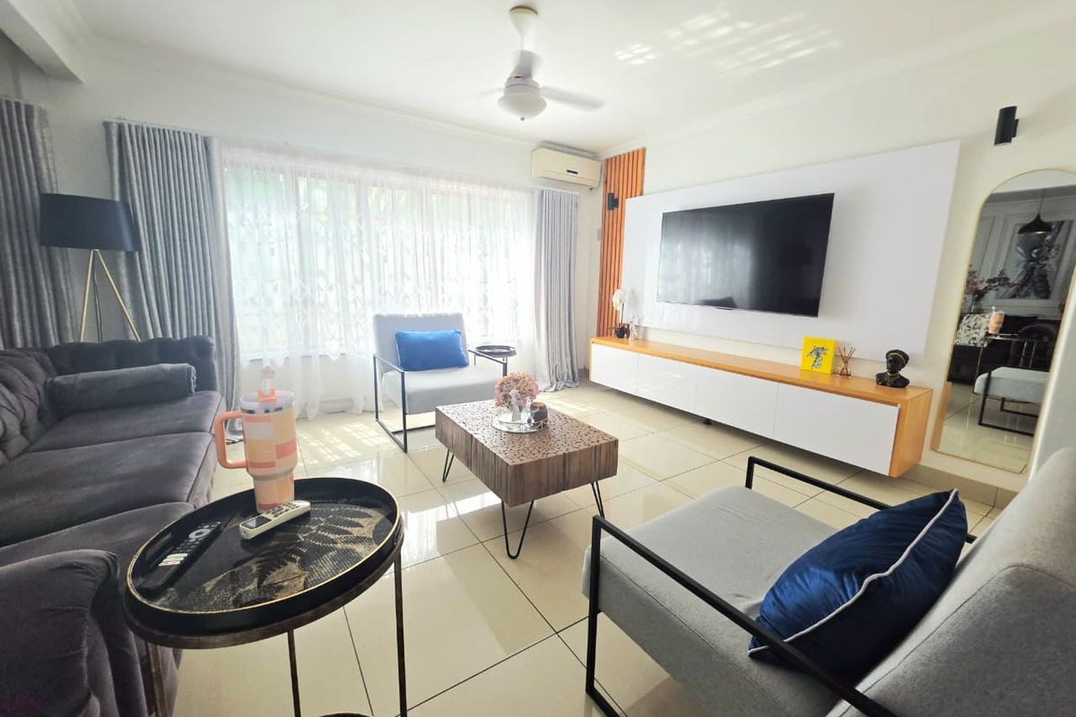 A bright and modern living room featuring tiled flooring, a built-in media console, ceiling fan, and wall-mounted air conditioning unit.