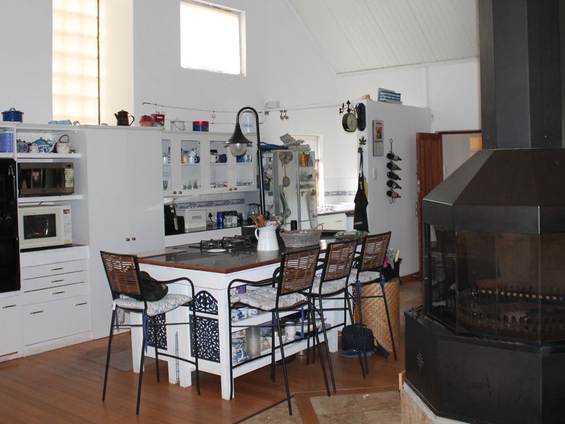 Open-plan kitchen and living area featuring a central island, built-in appliances, vaulted ceilings, and a prominent freestanding fireplace.