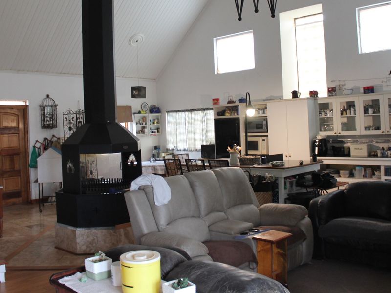 Spacious open-plan living area featuring a vaulted ceiling, a central freestanding fireplace, and a functional kitchen with built-in cabinetry and an island.