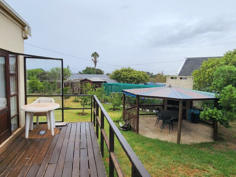 Rear view of the property featuring a timber deck, a garden area, and a covered outdoor entertainment space with a built-in braai.