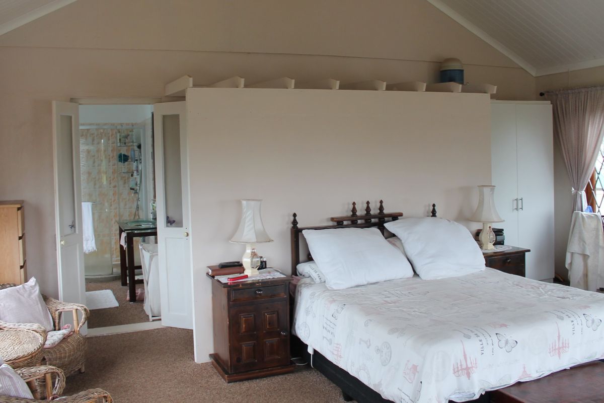 A bedroom featuring a vaulted ceiling, built-in wardrobe, and direct access to an en-suite bathroom with a leaded glass window.