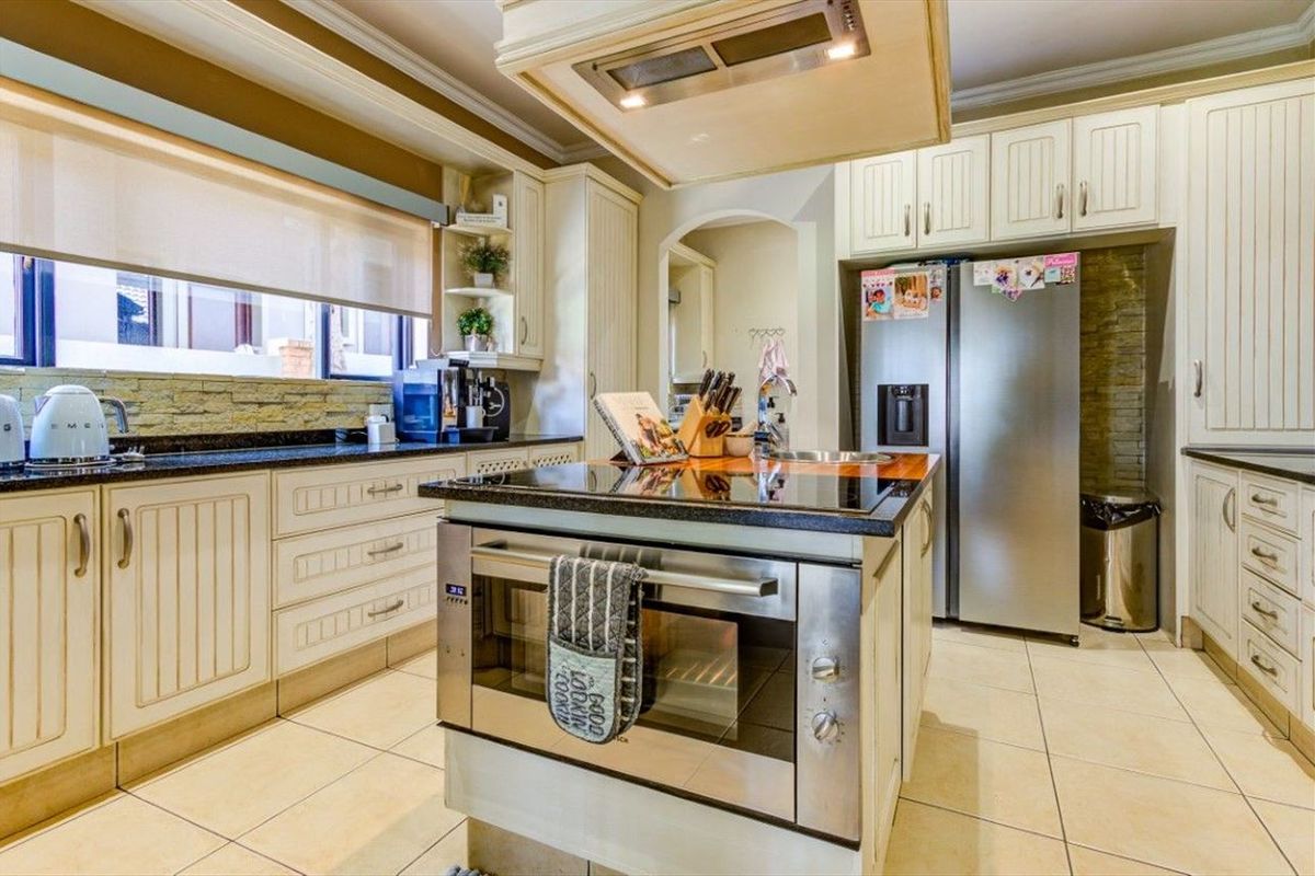A well-appointed kitchen featuring a central island with a built-in oven and cooktop, stone countertops, and ample cabinetry for storage.