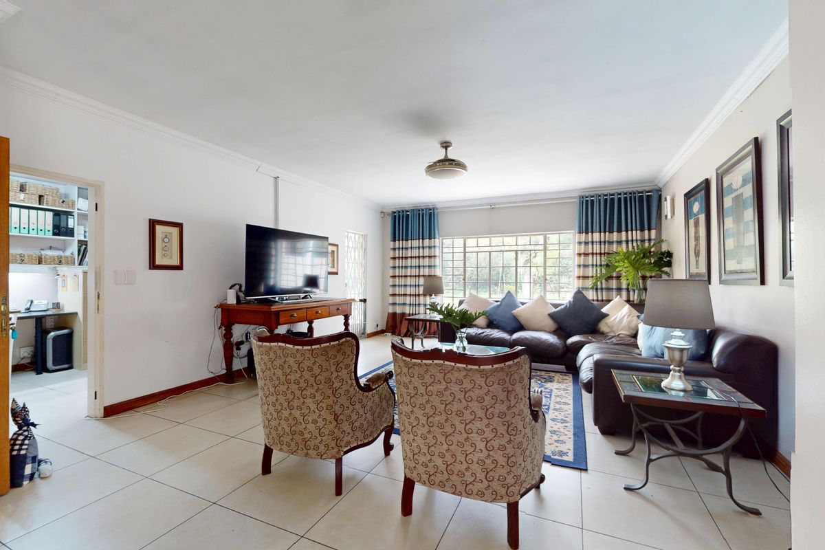 Spacious living room featuring neutral tiled flooring, ceiling fan, and large windows allowing natural light, providing a comfortable and functional family space.