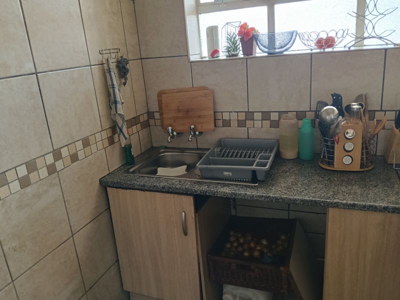 A compact kitchen area featuring a stainless steel sink, granite countertop, and tiled backsplash with neutral wall finishes.