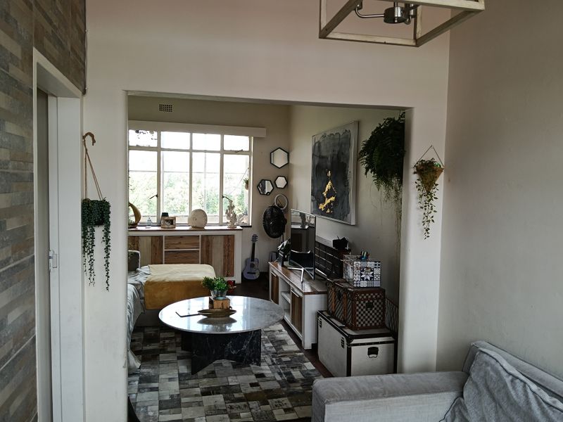A cozy living room featuring a large multi-pane window, built-in cabinetry, and a central ceiling light fixture.