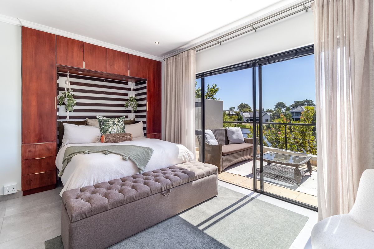 Spacious bedroom featuring built-in wooden cabinetry, tiled flooring, and large sliding glass doors opening onto a private balcony with scenic views.