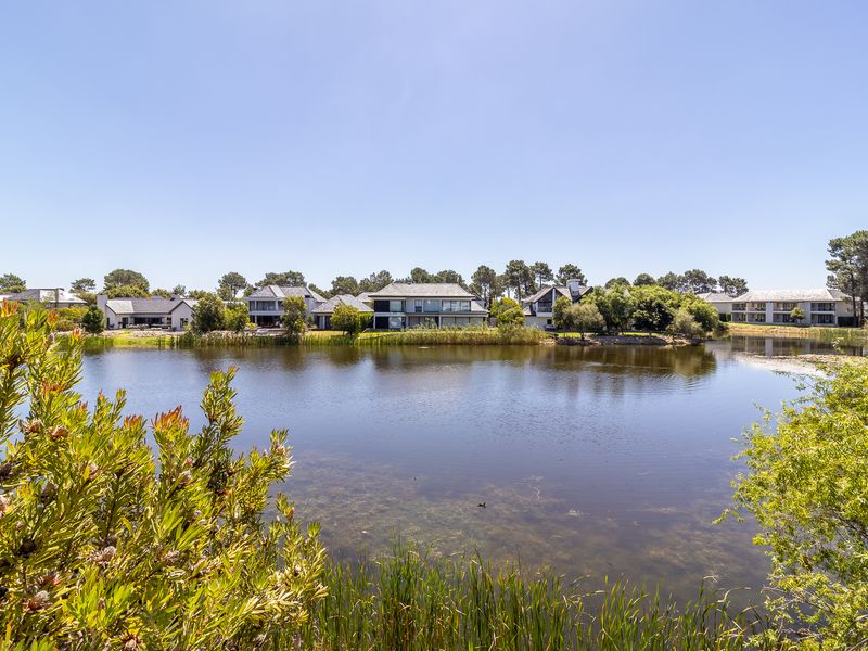 A scenic view overlooking a tranquil estate lake, showcasing the surrounding residential townhouse architecture and lush landscaped greenery.