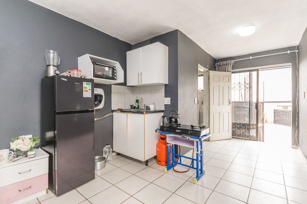 Compact kitchen area featuring tiled flooring, basic cabinetry, and direct access to an outdoor patio space.