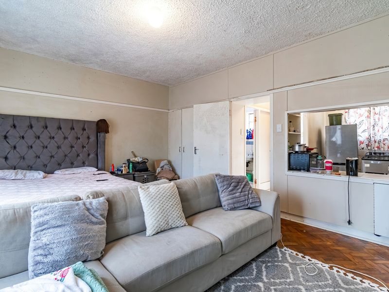 Open-plan living and sleeping area featuring classic parquet flooring, built-in storage, and a convenient serving hatch connecting to the kitchen space.