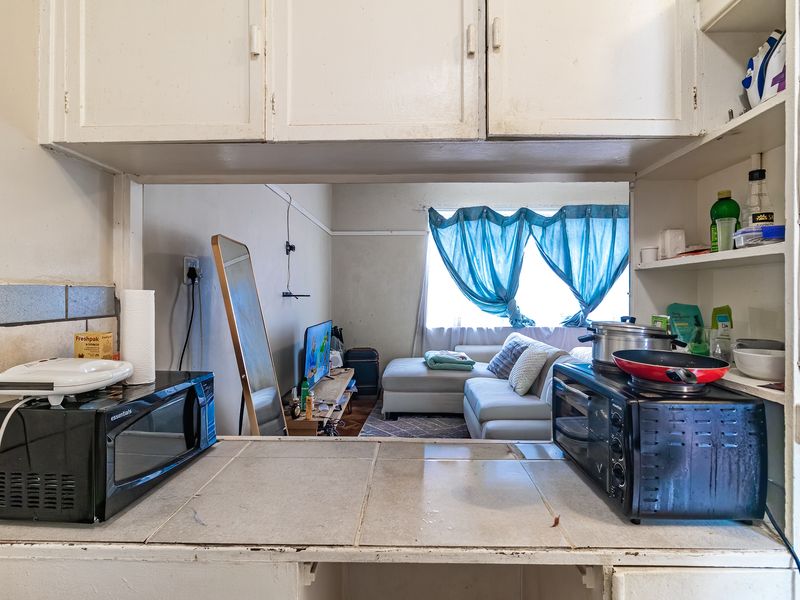 Open-plan kitchen area featuring tiled countertops and built-in cabinetry, looking through to the adjacent living space.