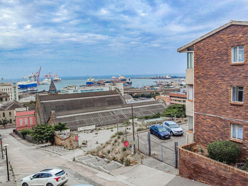 Elevated urban view overlooking the harbour, industrial port area, and surrounding city architecture from the perspective of a residential building.