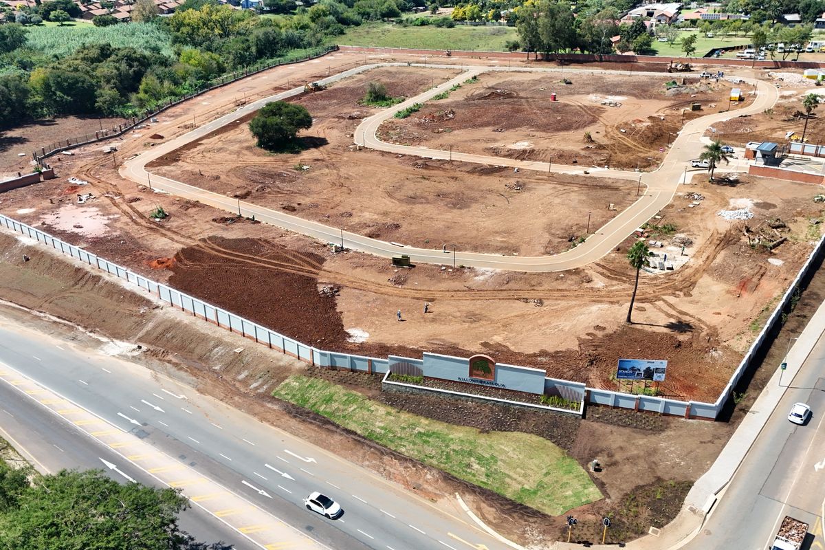 Aerial view of a residential development site featuring paved internal roads, perimeter walling, and established entrance signage.