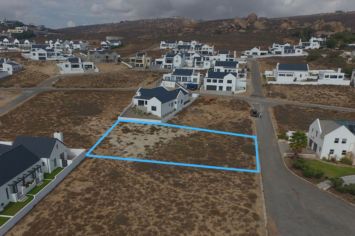 An aerial view of a vacant residential plot in a developed coastal estate, highlighting the property boundaries and surrounding neighborhood infrastructure.