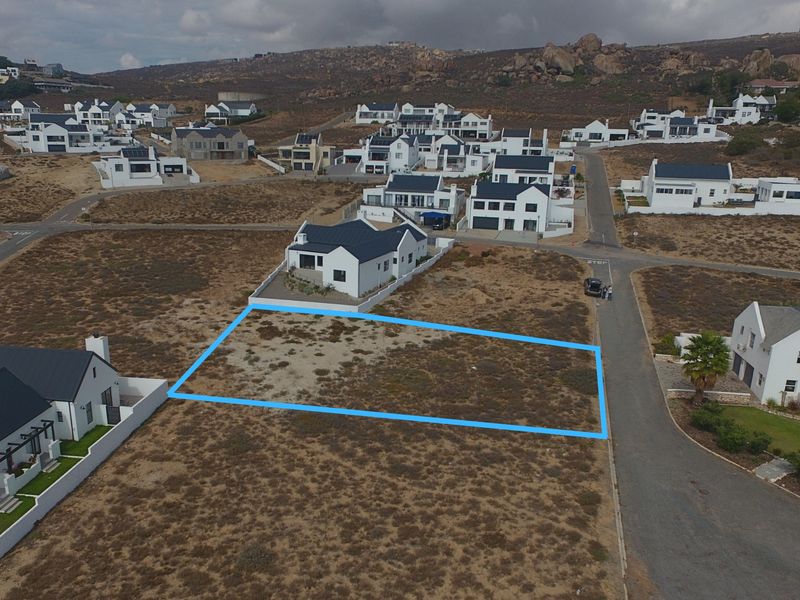 An aerial view of a vacant residential plot in a developed coastal estate, highlighting the property boundaries and surrounding neighborhood infrastructure.
