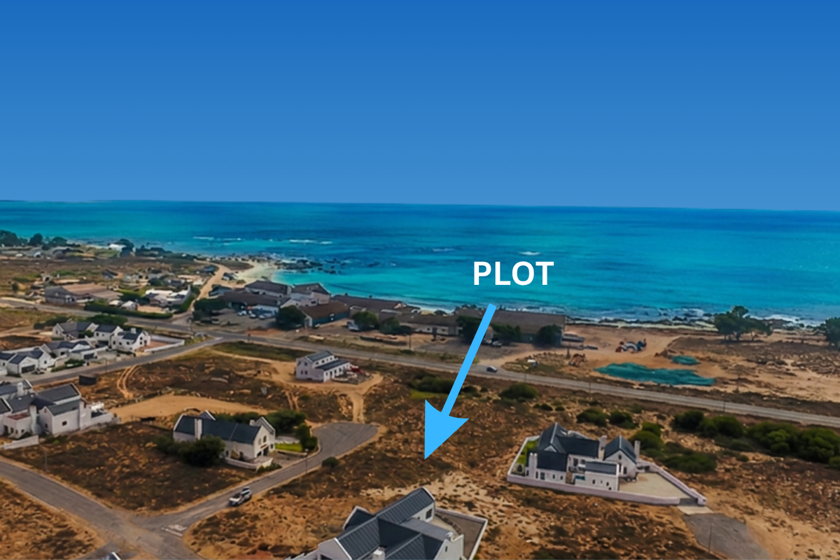 An aerial view of a vacant residential plot situated in a coastal neighborhood with ocean views.
