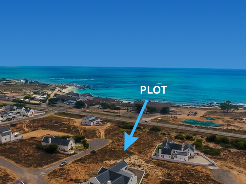 An aerial view of a vacant residential plot situated in a coastal neighborhood with ocean views.