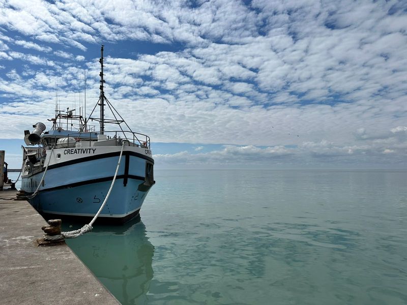 A view of a fishing vessel docked at a concrete pier overlooking the open water.