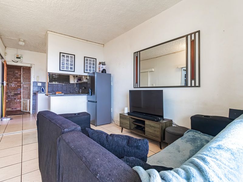 Open plan living area featuring tiled flooring and a compact kitchen space with built-in cabinetry and countertops.