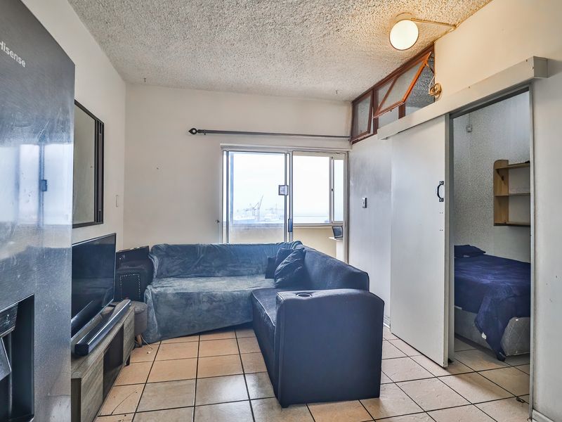 Open plan living area featuring tiled flooring, a sliding door to the balcony, and a sliding partition door leading to the bedroom.