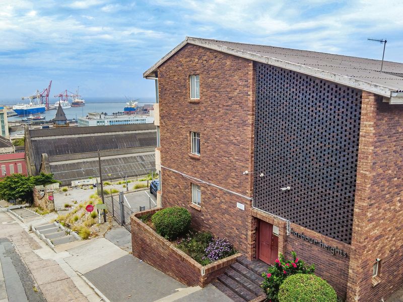 Exterior view of the Harbour Heights apartment building featuring a distinctive brick facade, decorative screen, and elevated position overlooking the harbor.
