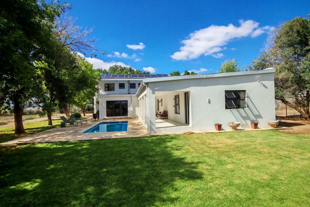 Rear view of the farmhouse featuring a swimming pool, covered patio area, and solar panels installed on the roof.