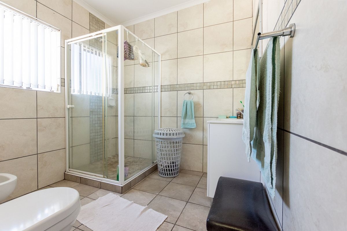 A functional bathroom featuring a glass shower enclosure, tiled walls and flooring, a vanity cabinet, and a bidet.