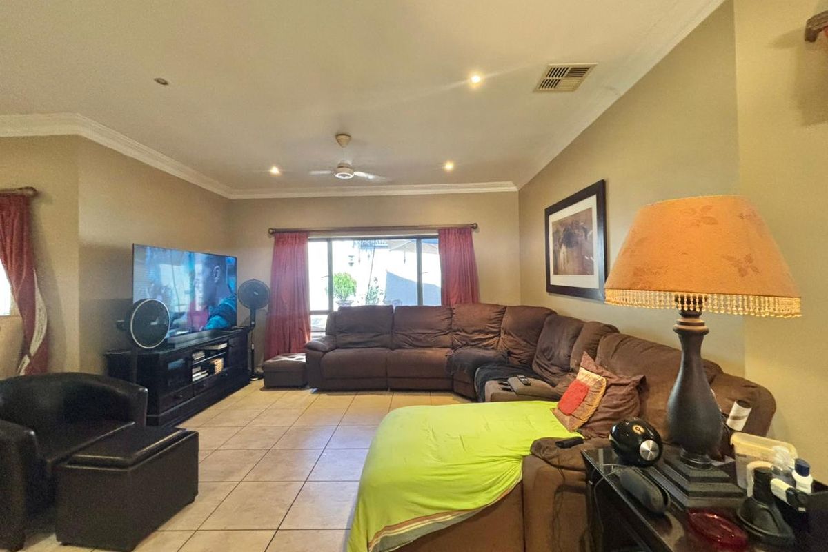 Spacious living room featuring tiled flooring, recessed downlighting, and a ceiling fan, providing a comfortable and functional family area.