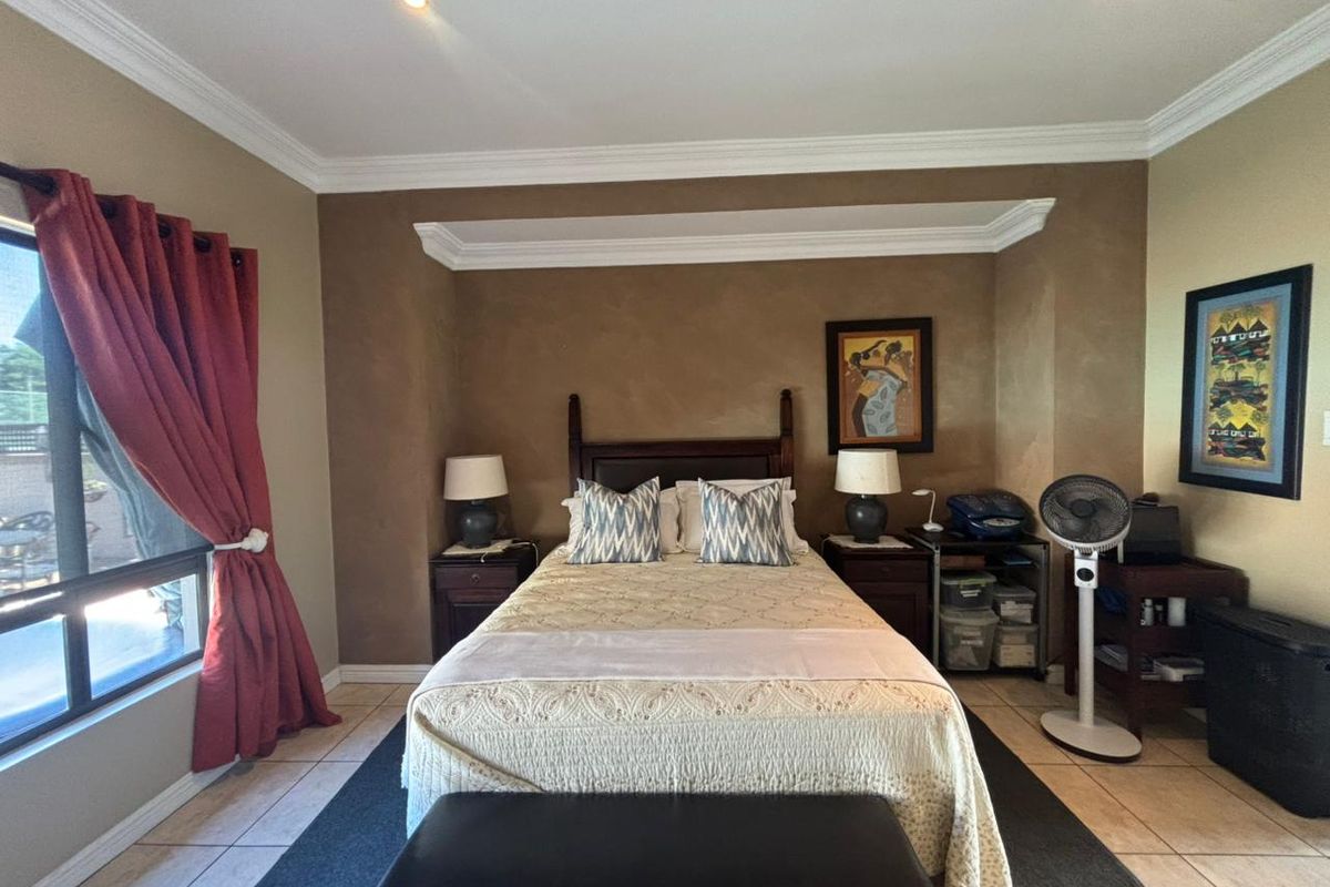 A bedroom featuring tiled flooring, recessed ceiling lighting, and decorative crown molding with a textured feature wall.
