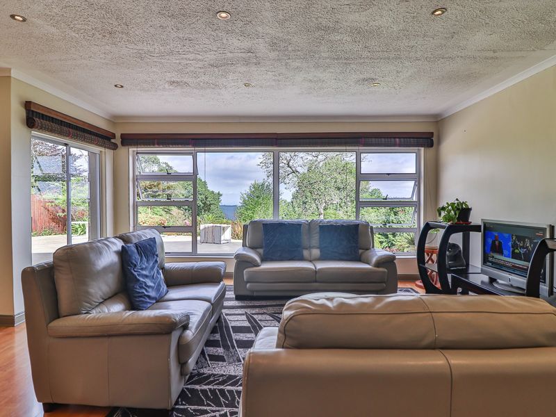 Spacious living room featuring large windows with garden views, recessed downlights, and laminate flooring, offering a bright and comfortable atmosphere.