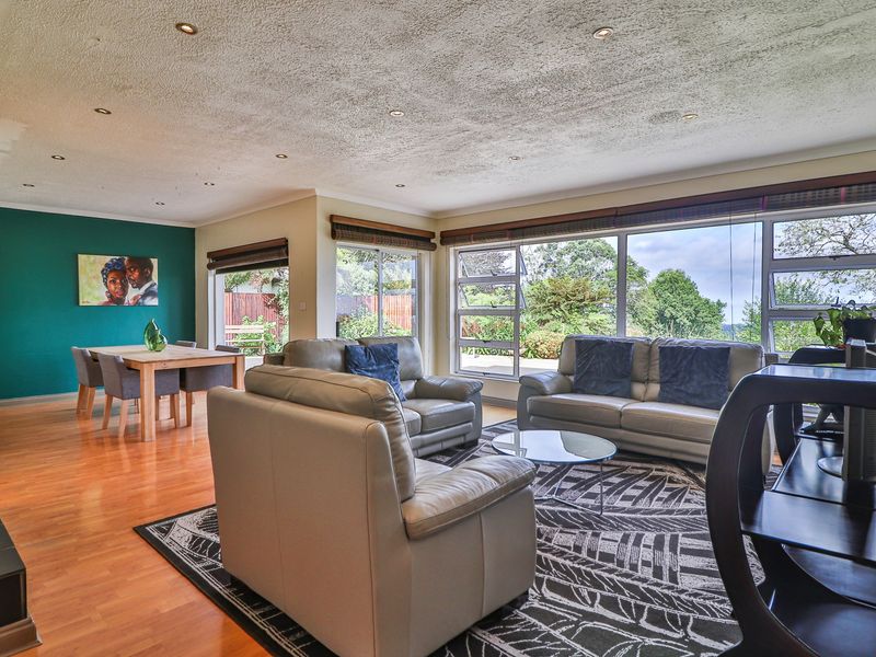 Spacious open-plan living and dining area featuring hardwood floors, recessed lighting, and large windows providing ample natural light and garden views.