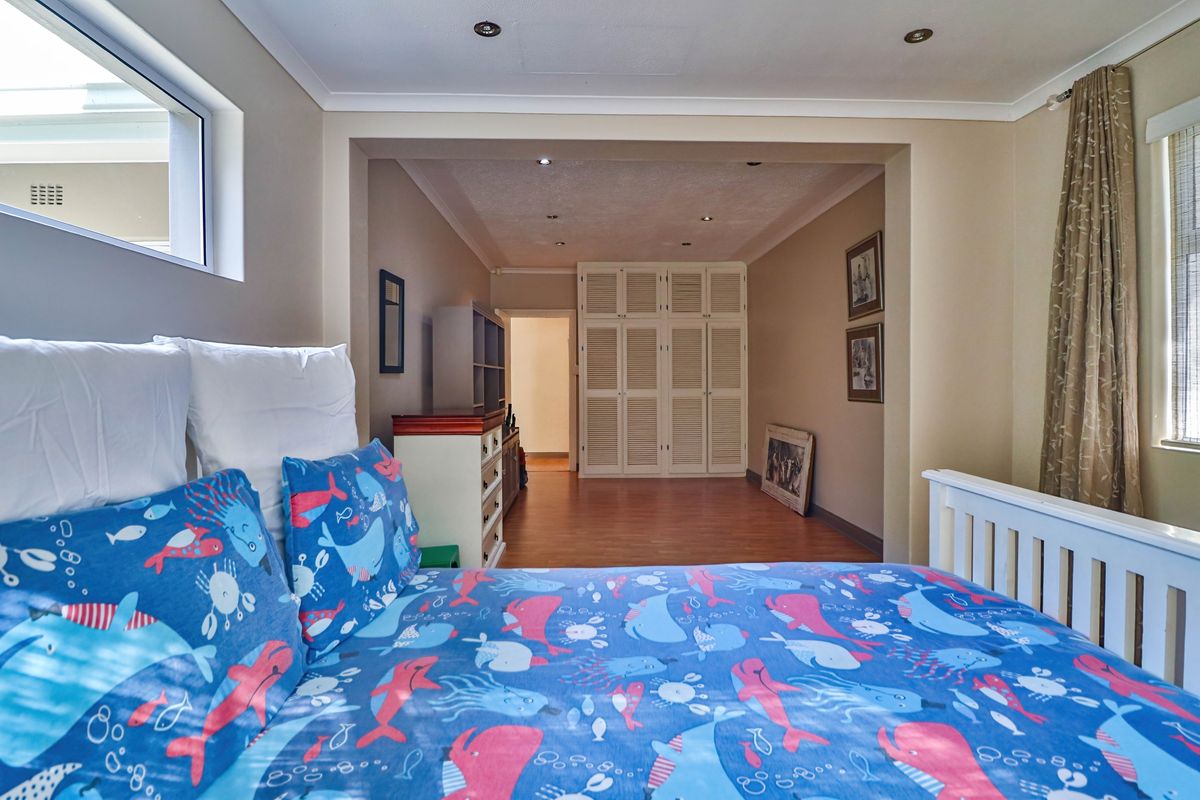 Spacious bedroom featuring built-in cupboards, laminate flooring, and recessed downlighting, offering a functional layout with a dedicated dressing or storage area.